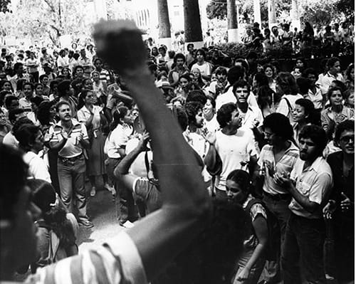 Man with fist in air in foreground of a protest